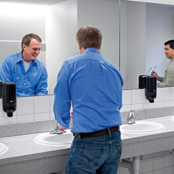 Badeværelse med 2 mænd der bruger Tork S1 sorte dispensere. Sæbedispenserne er placeret lige under spejlene
